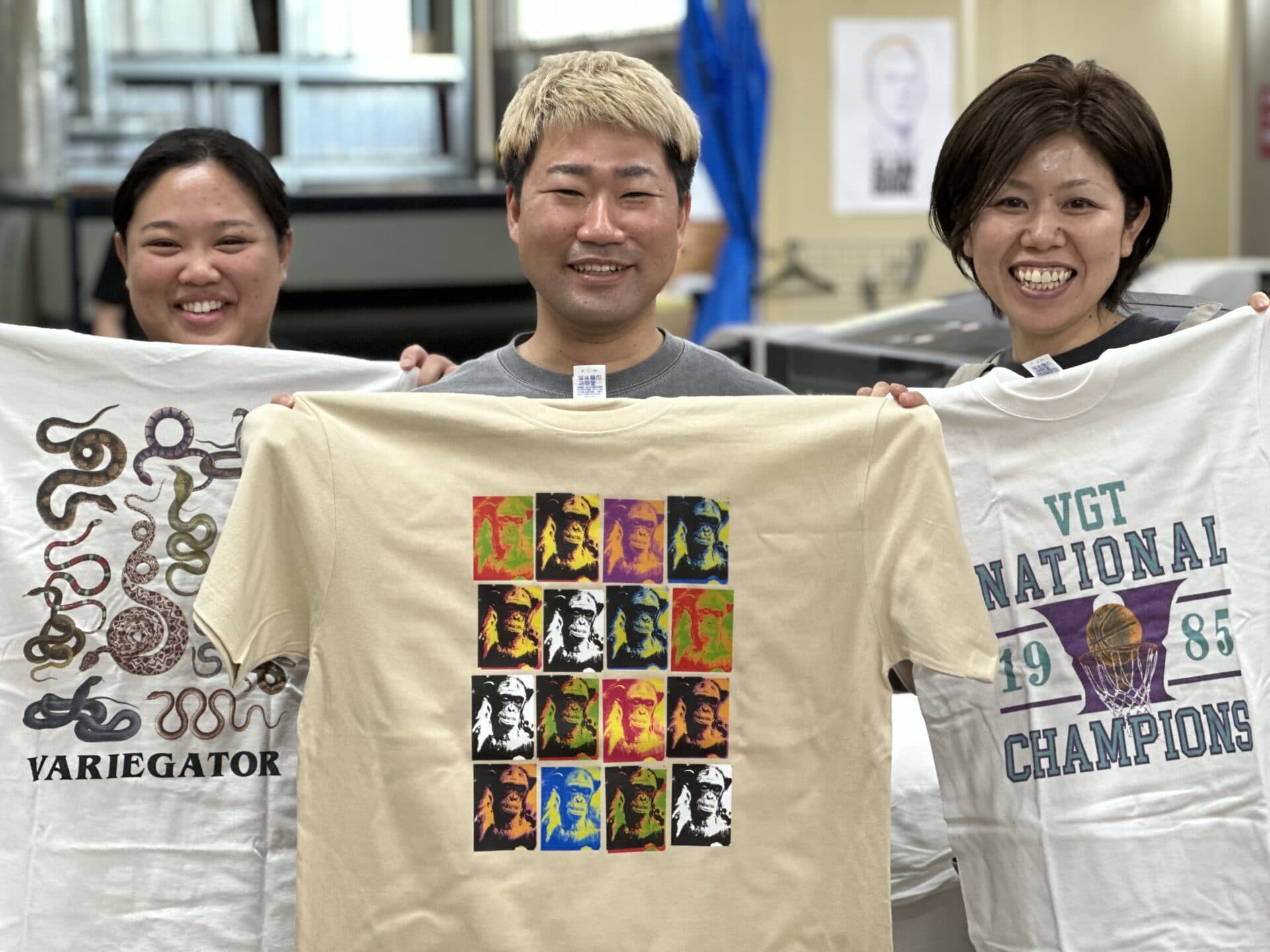 仕上がったTシャツを手に笑うスタッフ