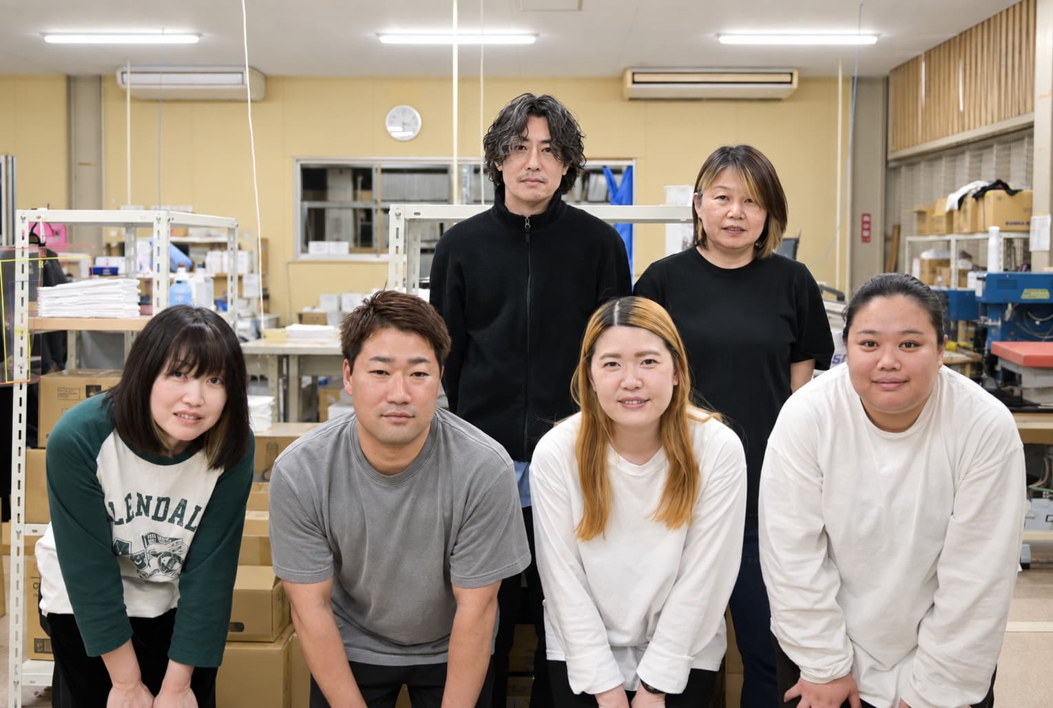 工場で笑顔で並ぶスタッフ6人